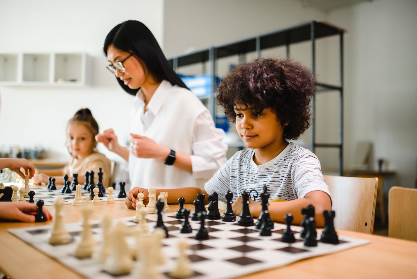 Una maestra observa a un niño que juega ajedrez en el aula