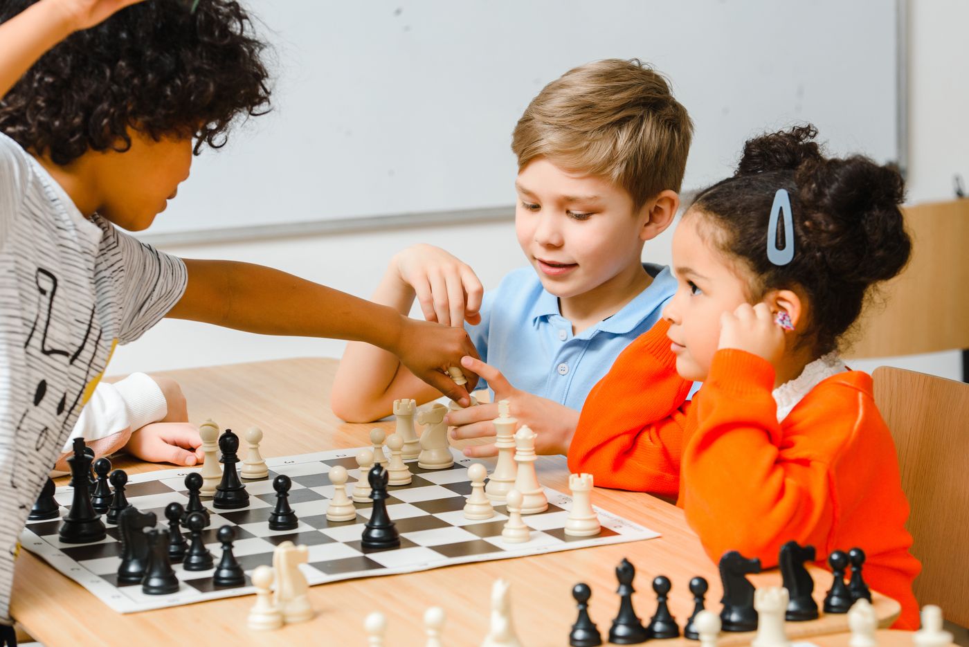 Grupo de niños jugando ajedrez en un aula, uno de ellos mueve una pieza